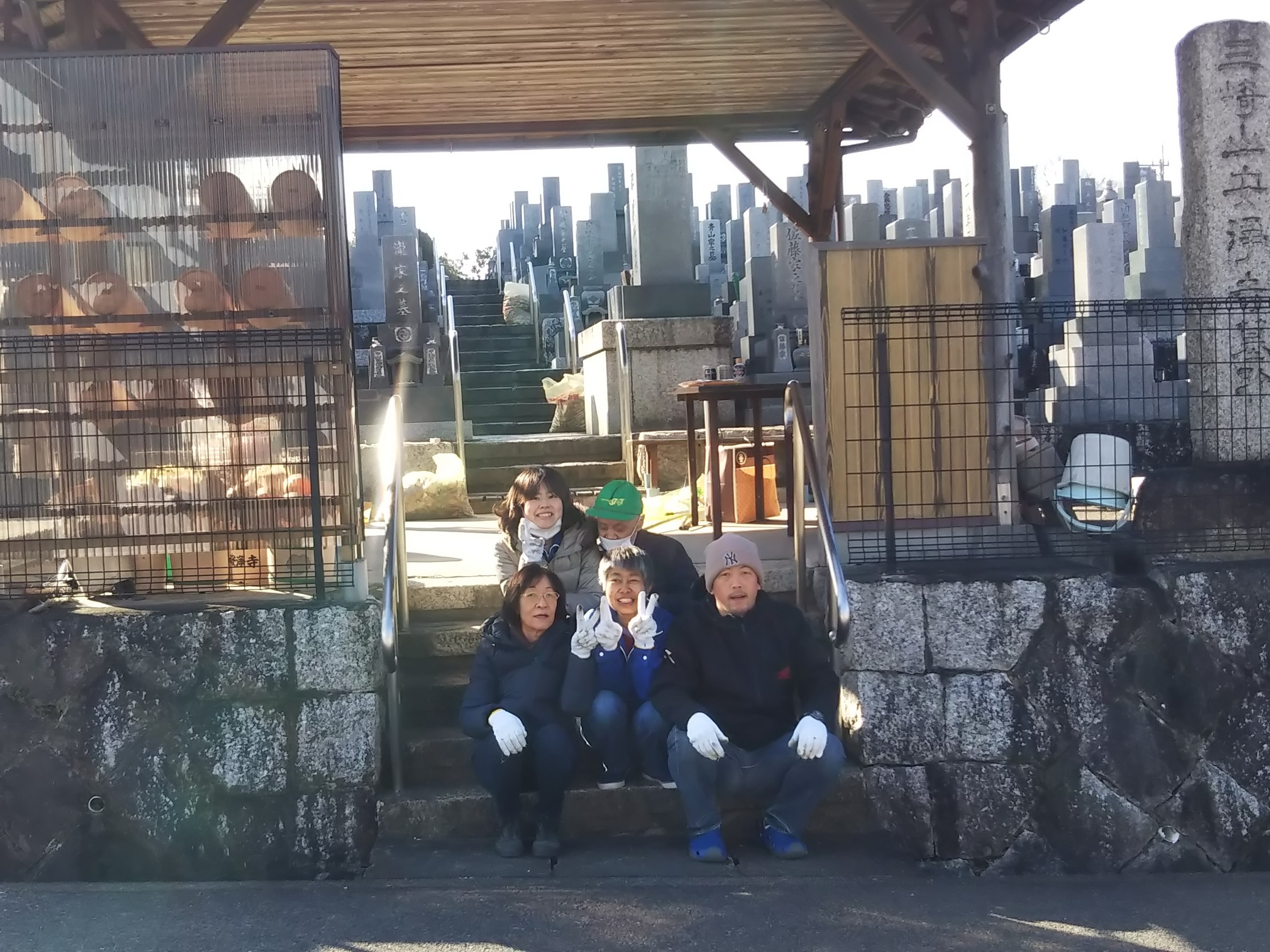 利用者とボランティアが墓地前の階段に座っている写真