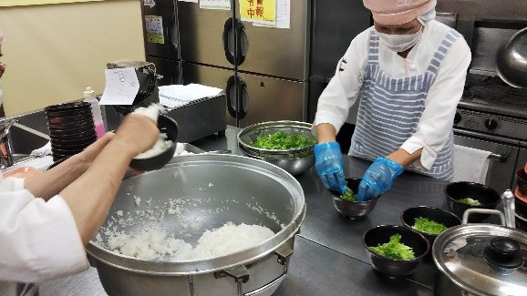 和風ロコモコ丼調理中　どんぶりにごはんをよそいレタスを盛り付けている写真