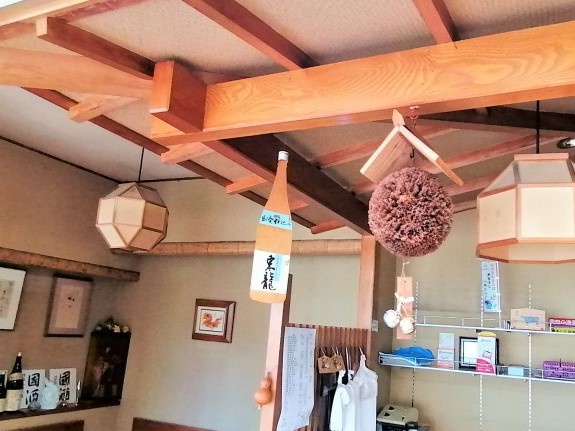 天井の梁から酒蔵ならではの杉玉が吊り下げられている写真