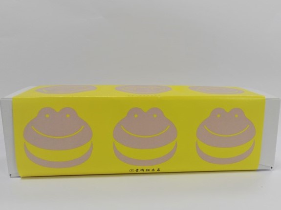 黄色の包装紙にカエルまんじゅうのイラストが３匹並んで描かれている可愛らしい写真