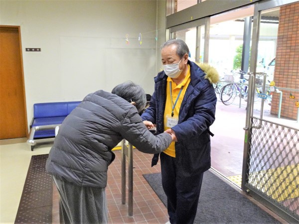 尾関さんがデイサービスから帰られる利用者さんの手を引いて歩いている写真