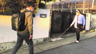 写真説明 歩行訓練士から街中での白杖を使った歩行訓練を受ける利用者の様子