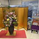 玄関に祝い花が飾ってあり、その横に職員手作りの小さな神社がある写真