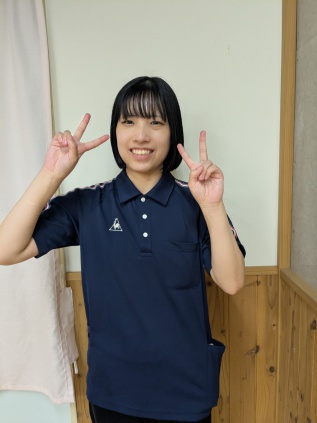 笑顔でピースをする横井支援員