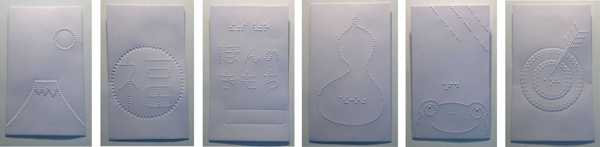 1 富士山の右上に太陽。 2 円の中に浮き出し漢字の福。 3 浮き出し文字ほんのきもちの上に点字。 4 ひょうたんの中央に点字でひょうたん。 5 下部分にかえるの顔、上部分には斜めに降る雨。 6 的に刺さった矢の先に点字であたり の写真